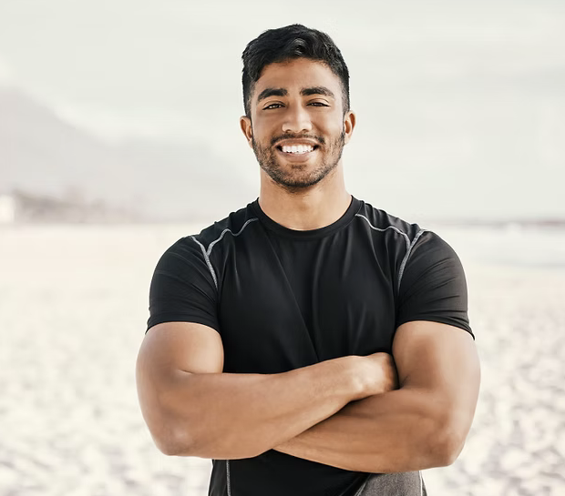Smiling man with arms crossed at the beach